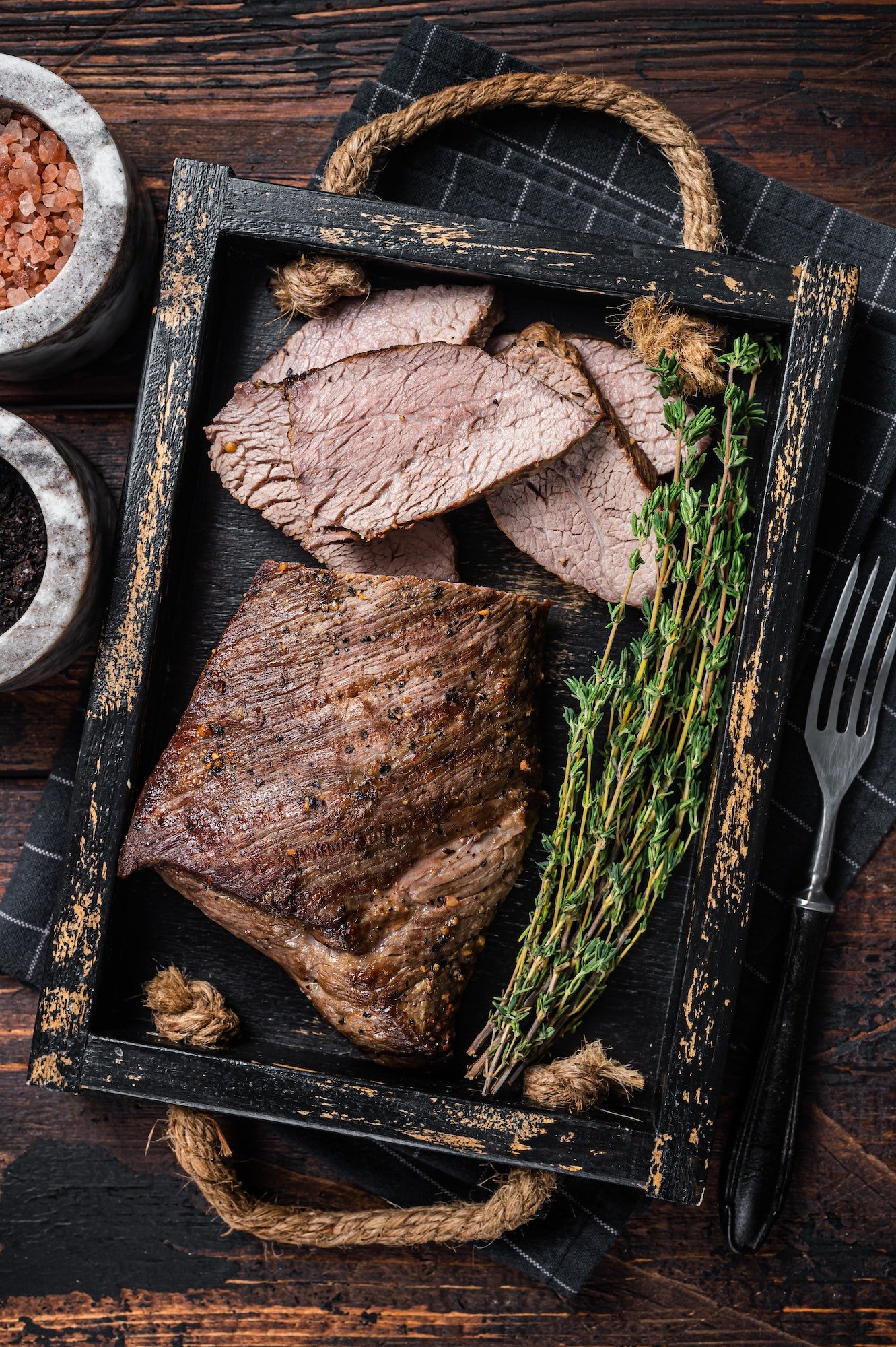 grilled-tri-tip-steak-sirloin-bottom-beef-in-a-tray-with-herbs-wooden-background-top-view.jpg